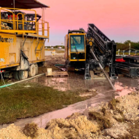 Two pieces of heavy drilling equipment are being used for a horizontal drilling project in Florida. The sun is setting in the background.